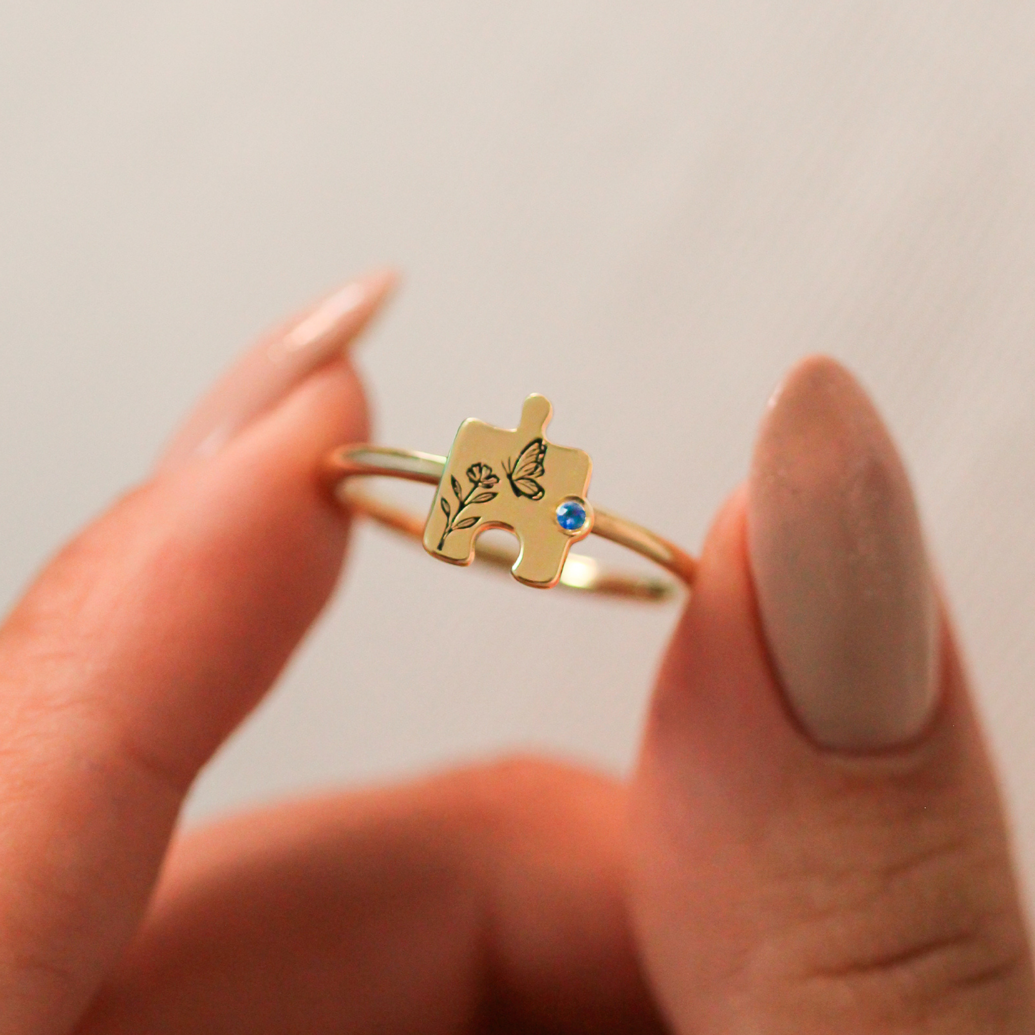 anel-personalizado-em-ouro-18k-com-quebra-cabeca-e-safira-azul-e-borboleta-para-autismo-e-mae-de-autistas
